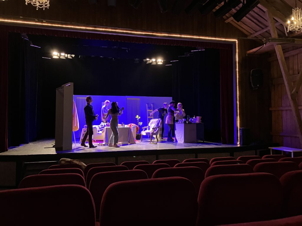 Bilden föreställer teatergruppen Palette som repar på scenen. I teatersalongen är stolarna tomma. 